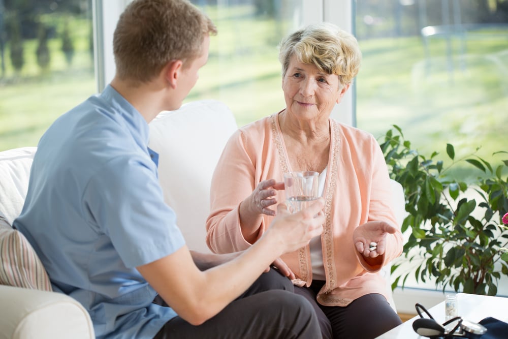 Young man giving medications to an older woman